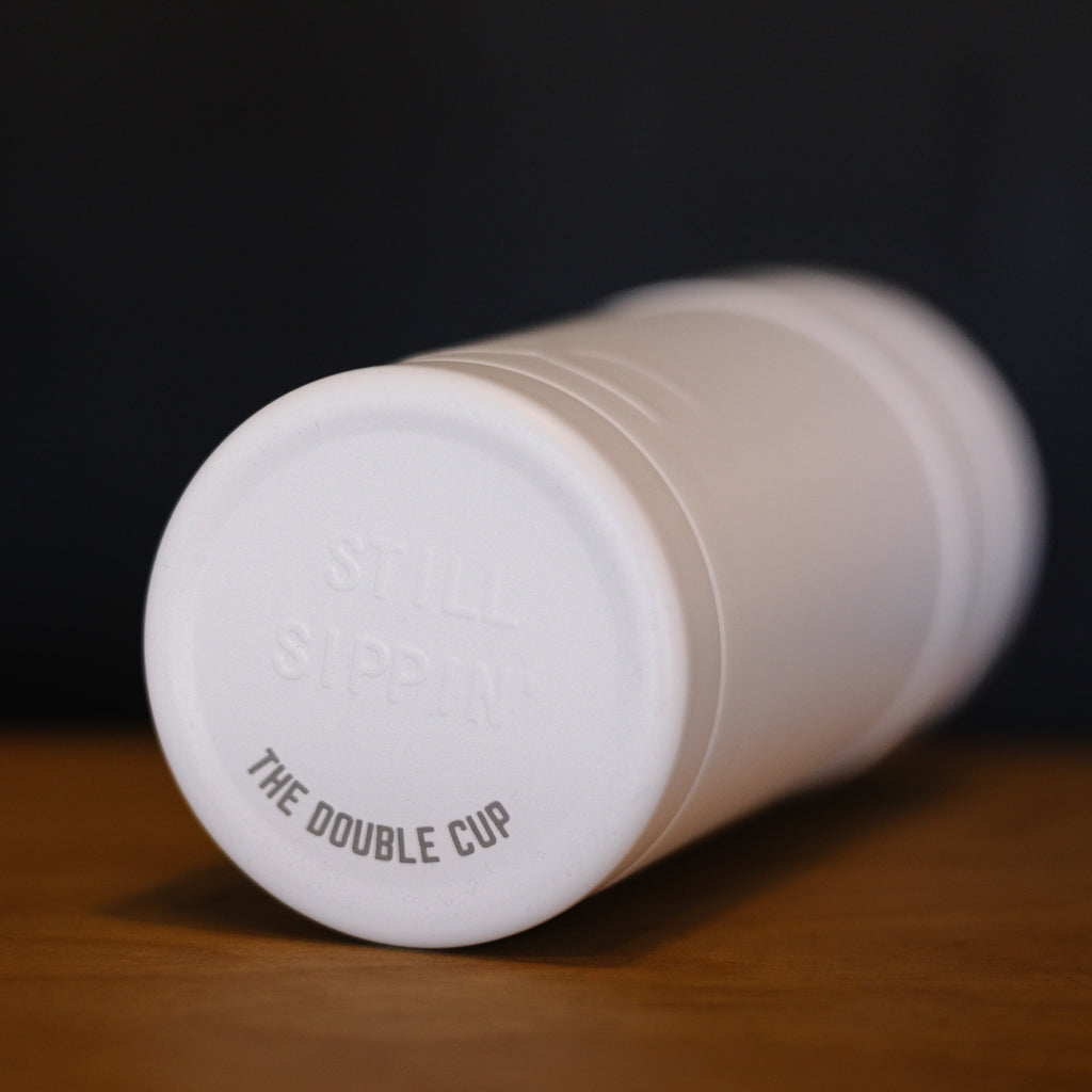 White tumbler with 'The Double Cup' branding on a wooden surface.