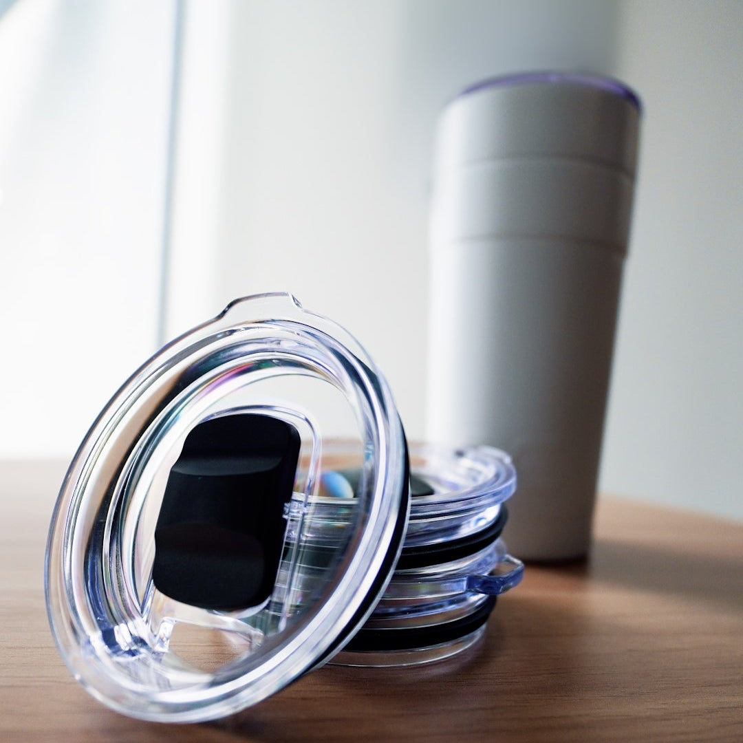 Stack of clear plastic lids on a wooden surface with a blurred background