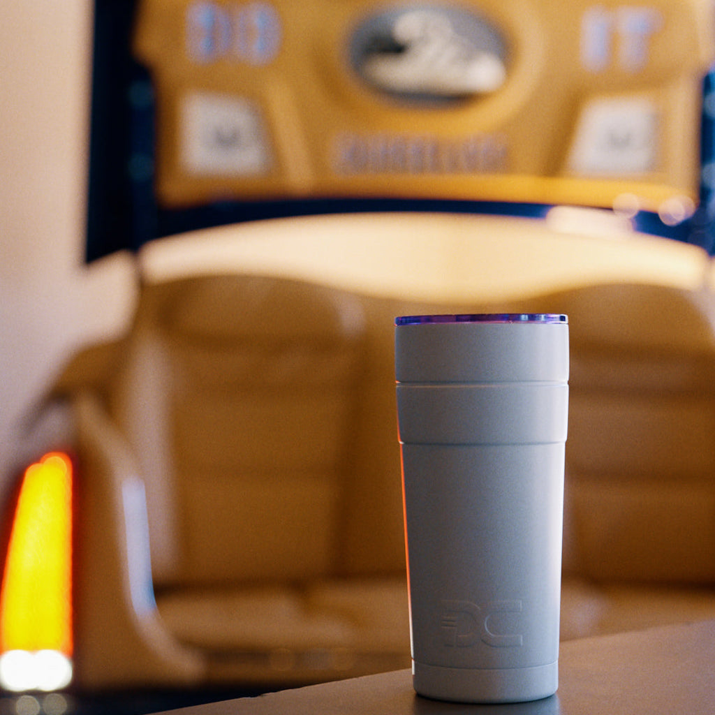 The Double Cup with purple lid on a table in front of a blurred background with a logo.